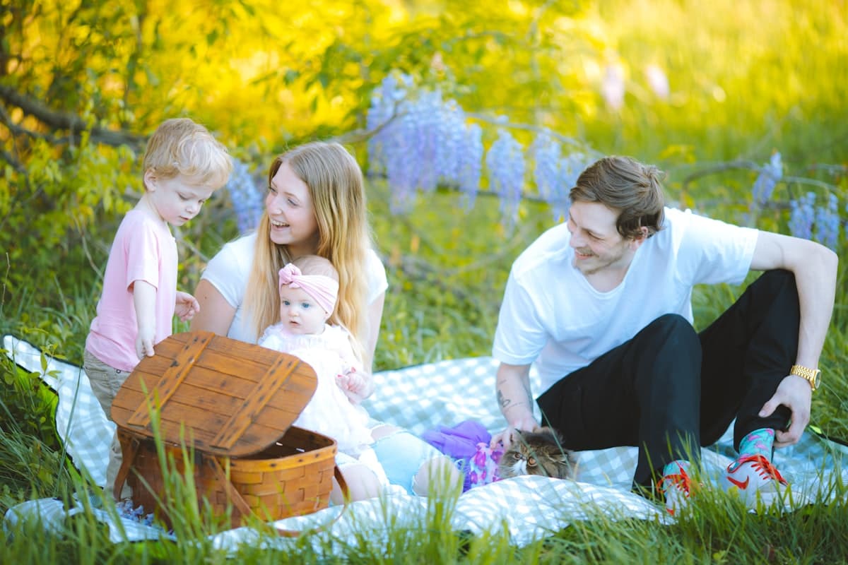 Familie på picnictæppe i solrigt græs